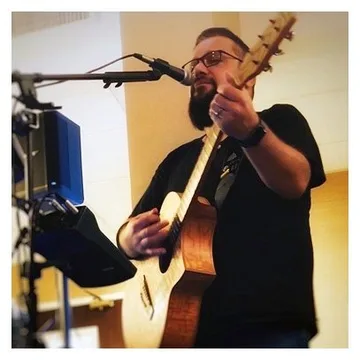 Rob Kosinski playing acoustic guitar and singing at a microphone